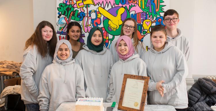 Group of young volunteers with certificate and cake